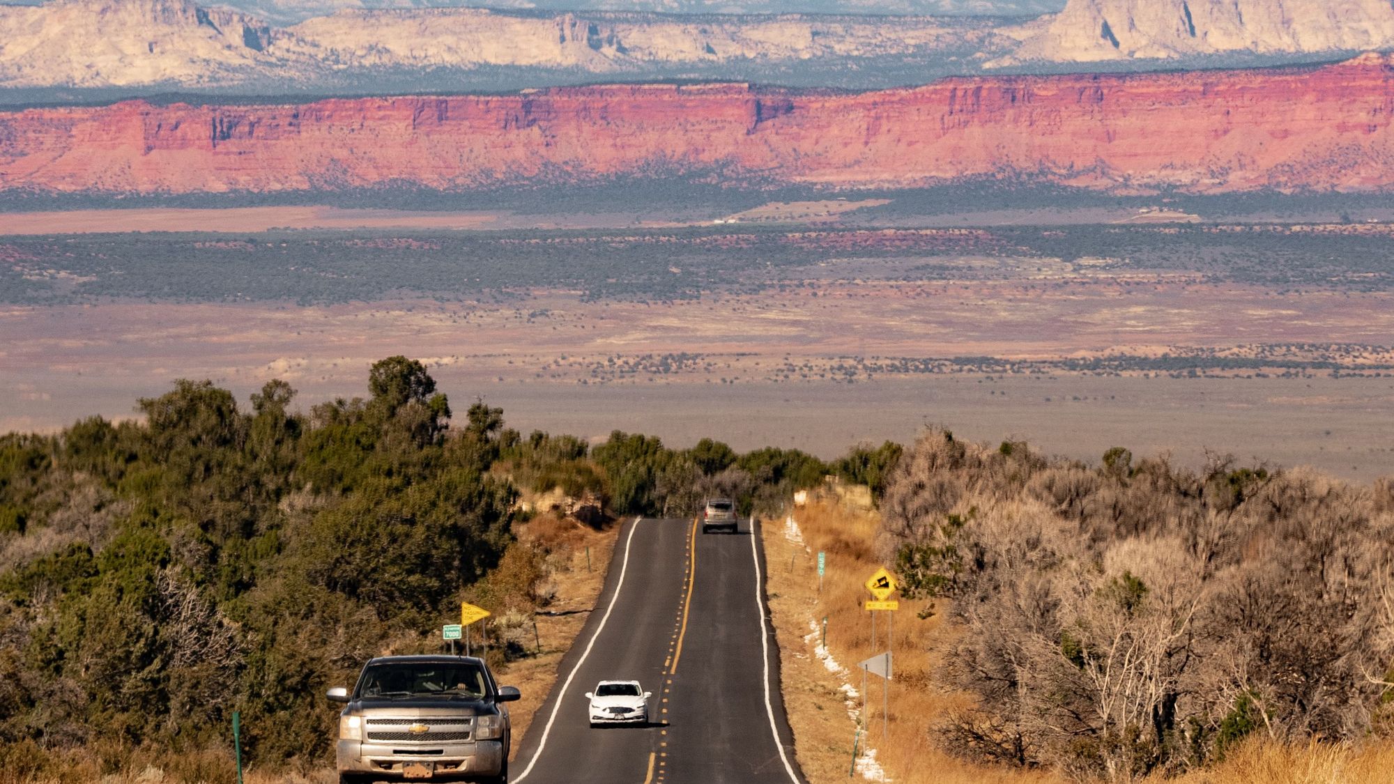 A highway running toward the red mesas of northern New Mexico